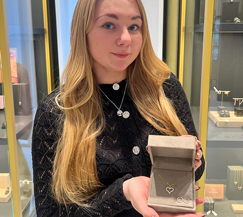 Medarbejder fremviser smykkesæt i butik.